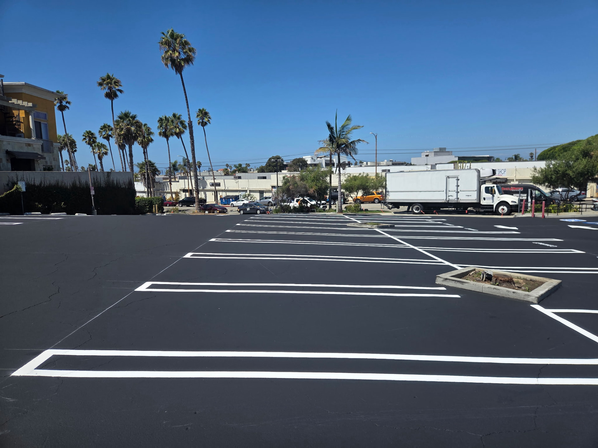 Ground-level view of completed white line striping on a freshly sealed parking lot in Redondo Beach, California